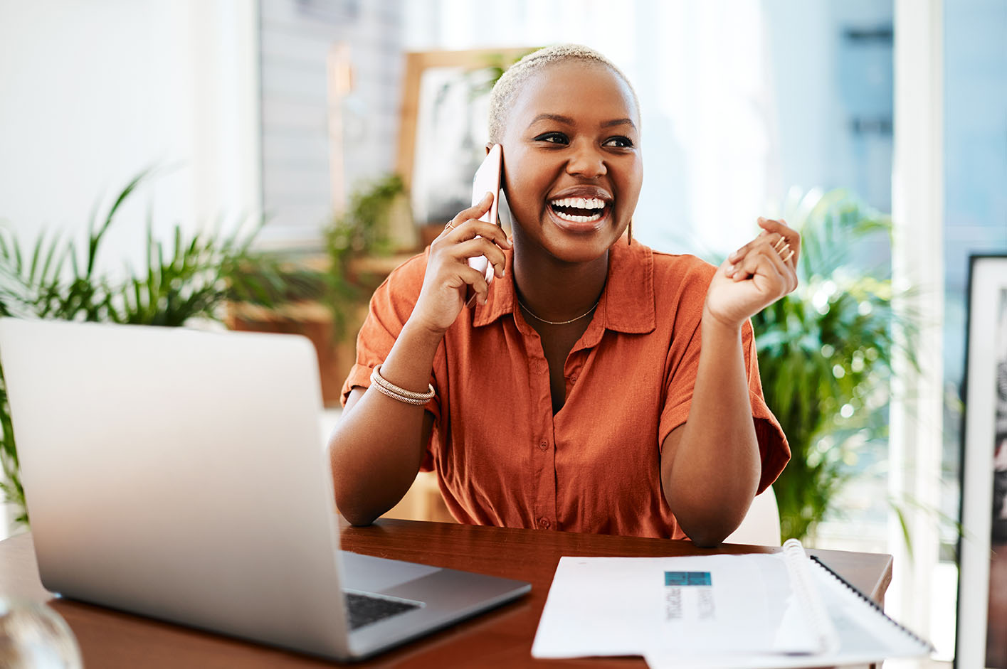 Woman laughing while talking on phone at desk